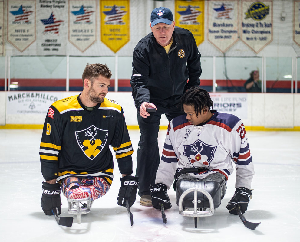 Two time US Paralympic Sled Hockey Gold Medalist and retired Marine Travis Dodson and Warrior for Life Fund Sled Team’s Zyree Fuller take ceremonial faceoff from Frank Simonetti during July’s WFLF Sled Hockey Showcase Game